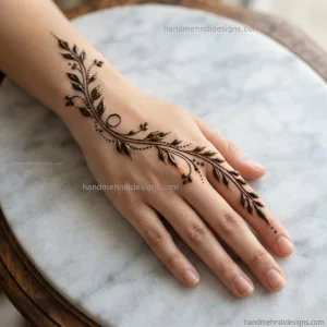 Simple back hand bel mehndi design with a diagonal leafy vine extending from the wrist toward the index finger.