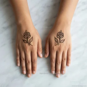 Easy back hand rose mehndi design with a tiny spiral flower, two leaves, and small dot accents.