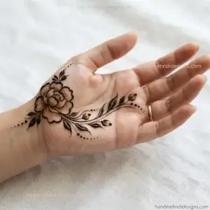 Simple thumb side floral mehndi with an open flower, curved leafy stem, buds, and dots