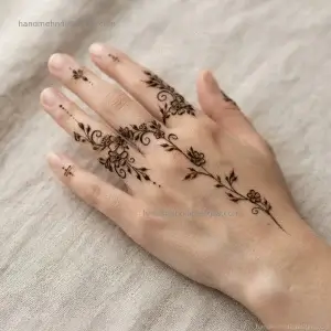 Finger-focused back hand floral vine mehndi with tiny flowers near the finger bases and a light leafy trail