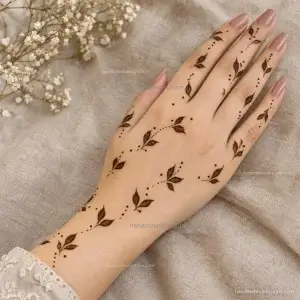 Scattered leaf mehndi motifs flowing from the wrist across the back hand