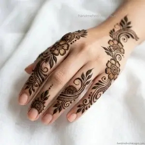 Arabic-style back hand diagonal mehndi with a bold curved vine, spaced flowers, pointed leaves, and decorative curls extending toward the index finger.